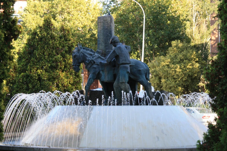 a statue of two men on horses is near the water fountains