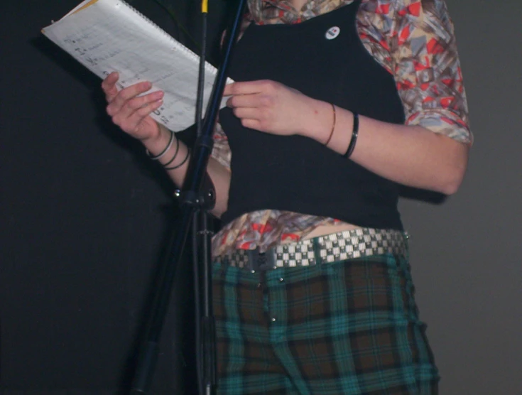 a woman in plaid skirt holding a book
