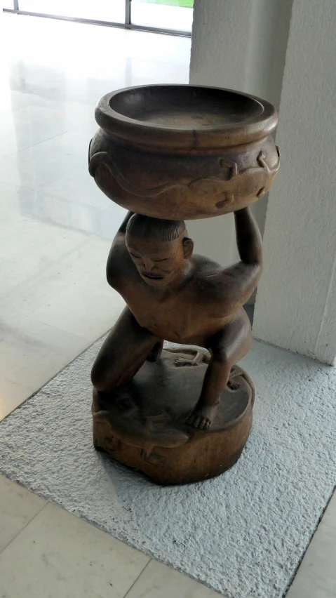 an elephant design vase sitting on top of a wooden pedestal