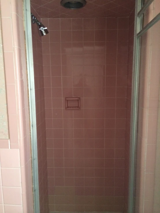 a pink tiled bathroom shower and toilet in progress