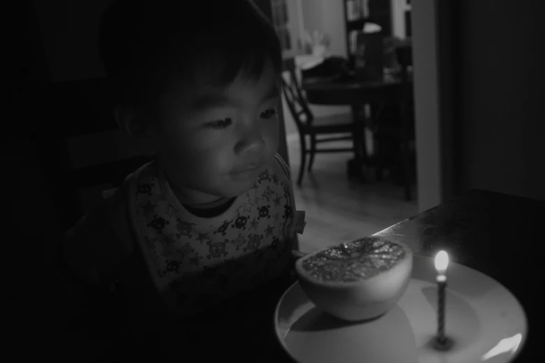 a boy sitting in front of a candle
