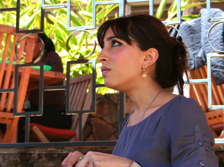 a woman in a gray shirt and gold earrings on her left hand