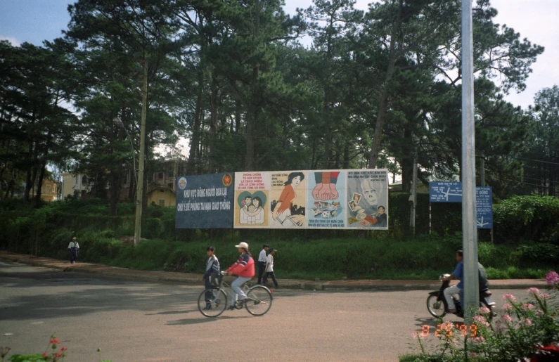 people riding their bikes down the road by some trees