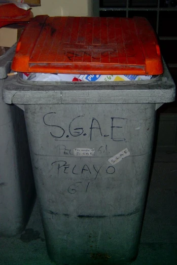 an orange plastic container with graffiti written on it