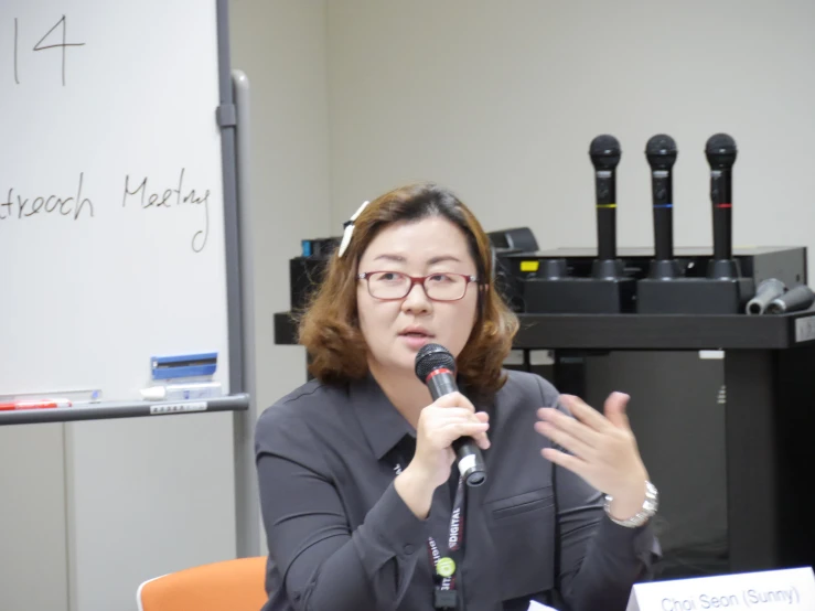 a woman holds a microphone and gestures while speaking