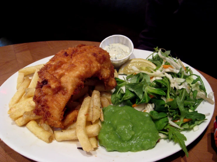 a plate filled with fries, cole slaw and garnish on top of a table