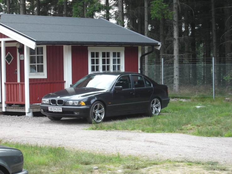 a black car parked outside a tiny home