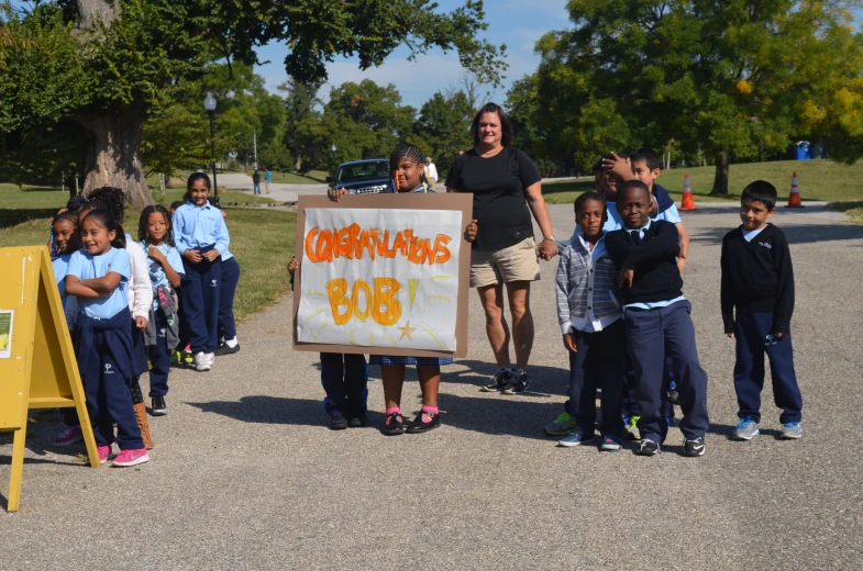 a woman and children with sign outside in the day