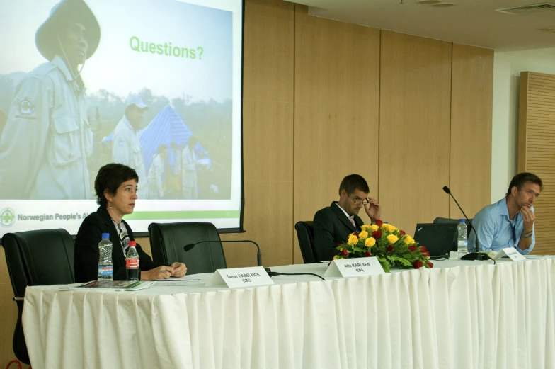 three people at a meeting with the speaker in front of them