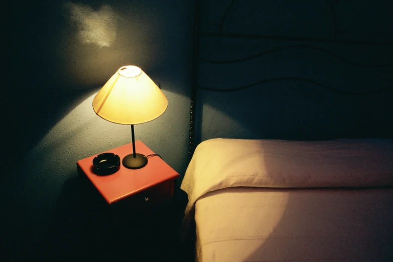 a lamp sitting on the nightstand next to a bed