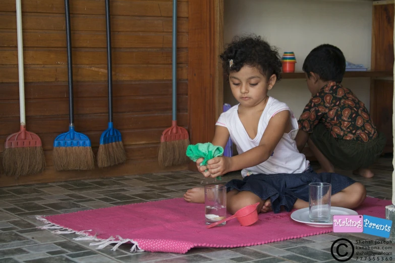 a little girl sitting on the floor playing with cups