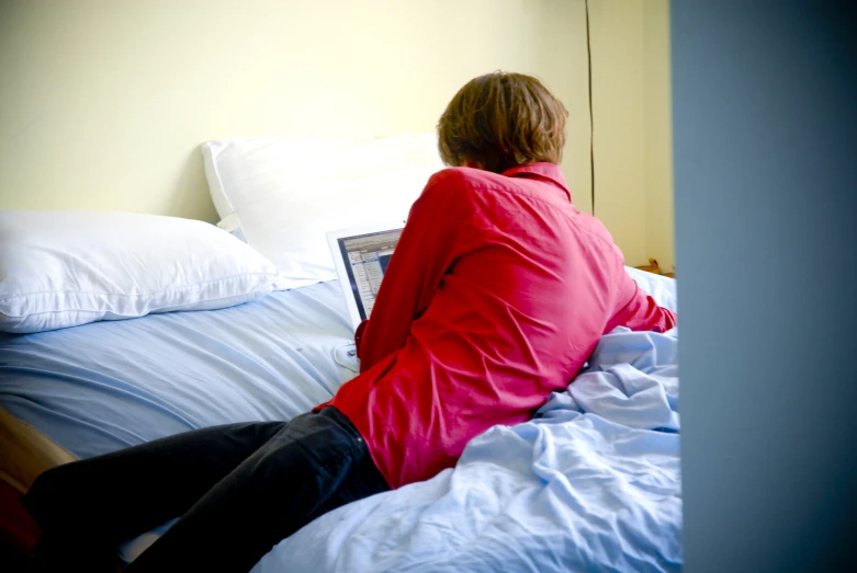 a woman in red sitting on the edge of her bed