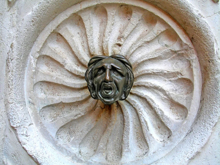 an unusual face in a large sculpture surrounded by white cement