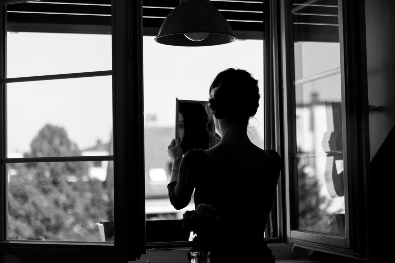 a woman standing by a window looking outside