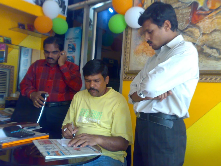 the man is looking at a newspaper in front of him