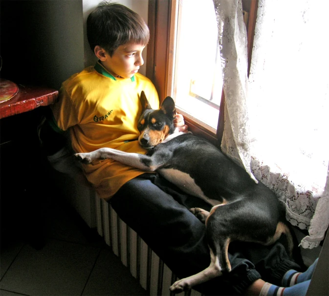 the boy is laying down with his dog