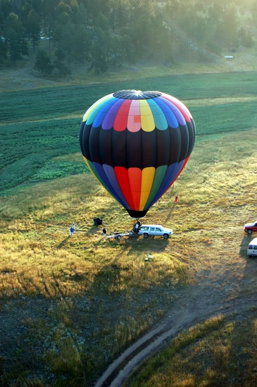 a  air balloon is seen from the air while some other vehicles stand nearby