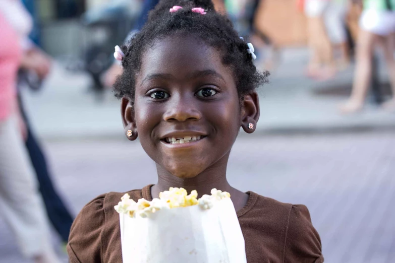 girl smiling while holding up a cake with yellow topping