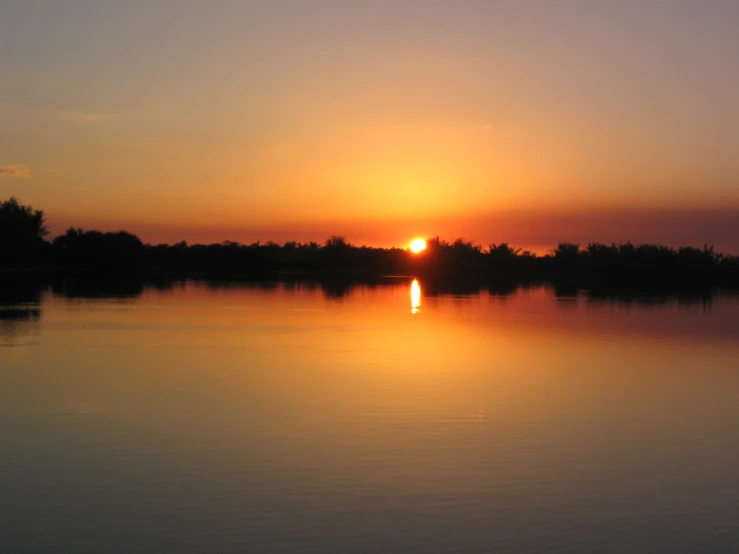 a sunset view looking across the water with trees in the background