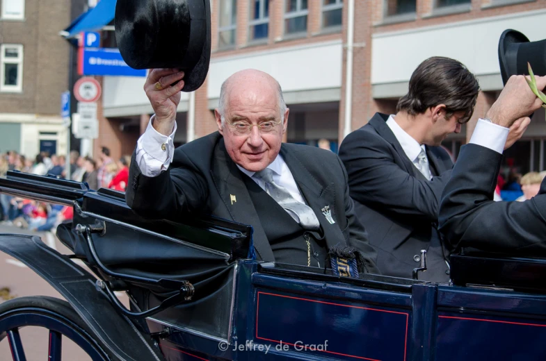 a group of men in suits ride in a horse drawn carriage