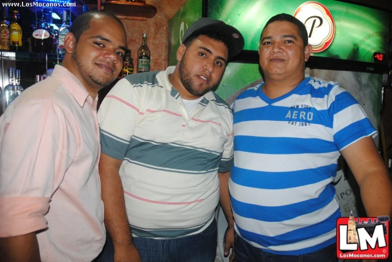 three guys are posing in front of a tv