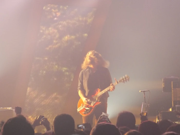 man playing guitar at large crowd in dark area