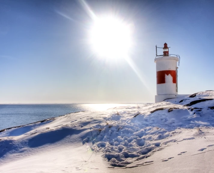 a red and white light house in the middle of snow