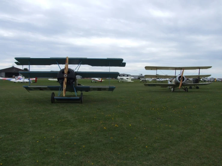 people standing next to two planes in a field