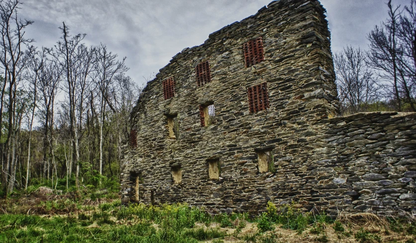 an old building with windows, grass, and trees