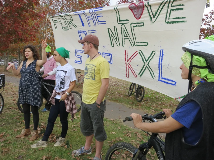 young people on bicycles holding up a banner with writing