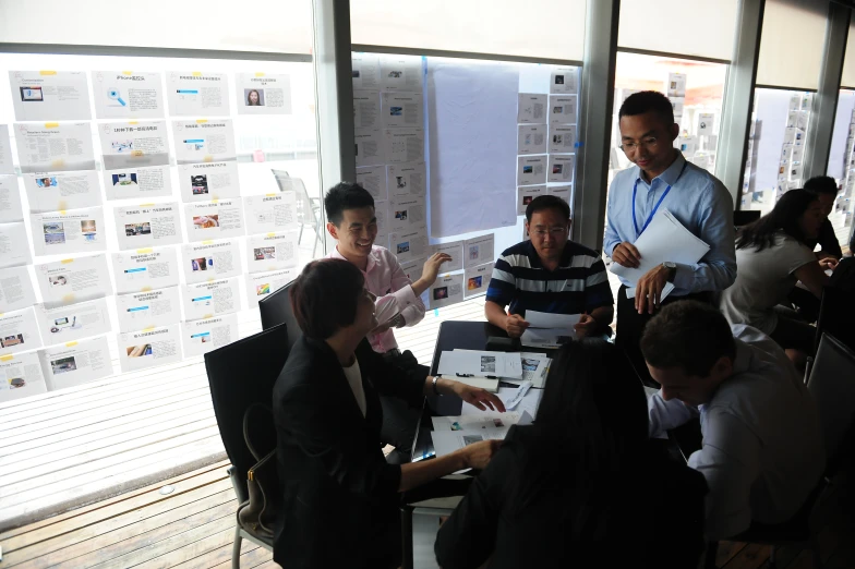 several people are gathered around a table in an office setting