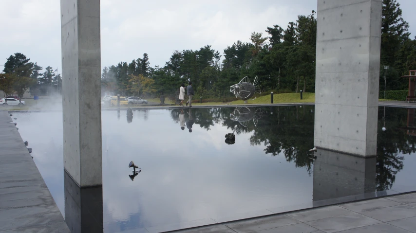 water reflecting two pillars in the background and some clouds in the sky