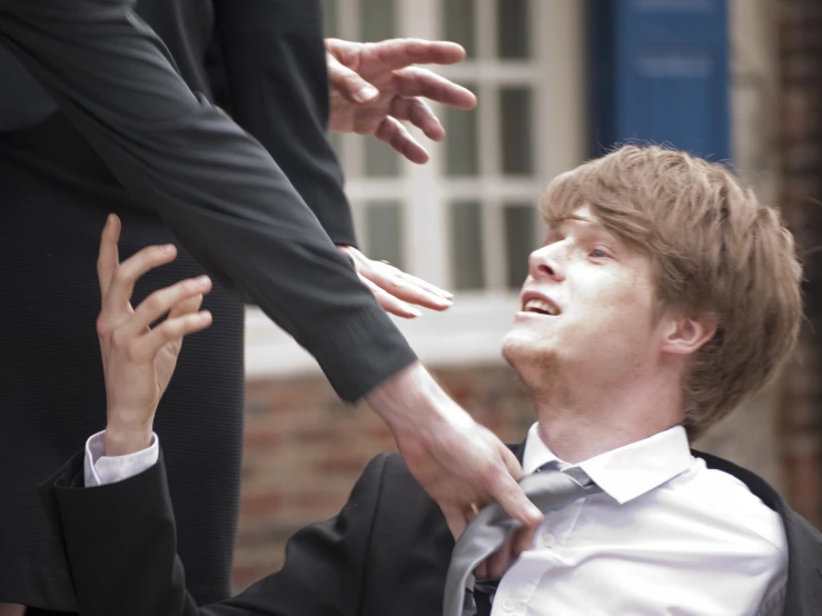 two men standing next to each other with one reaching out his hand