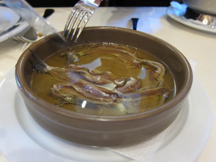 soup and vegetables on a white plate being eaten