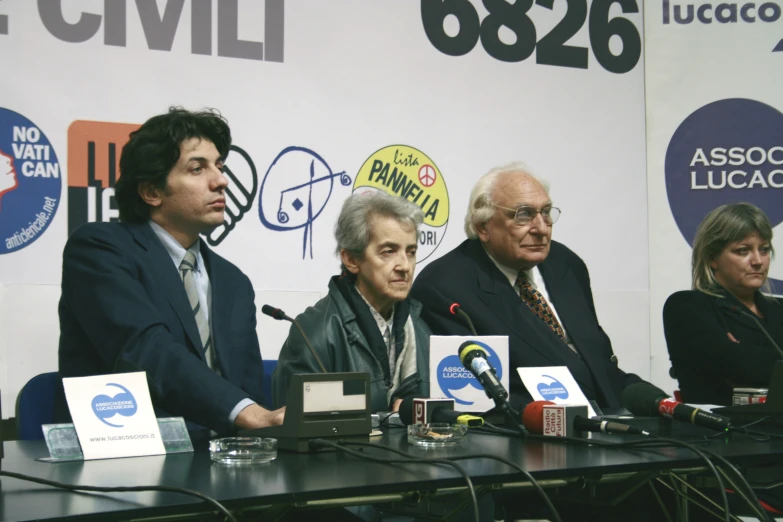 four people are sitting at a table with microphones