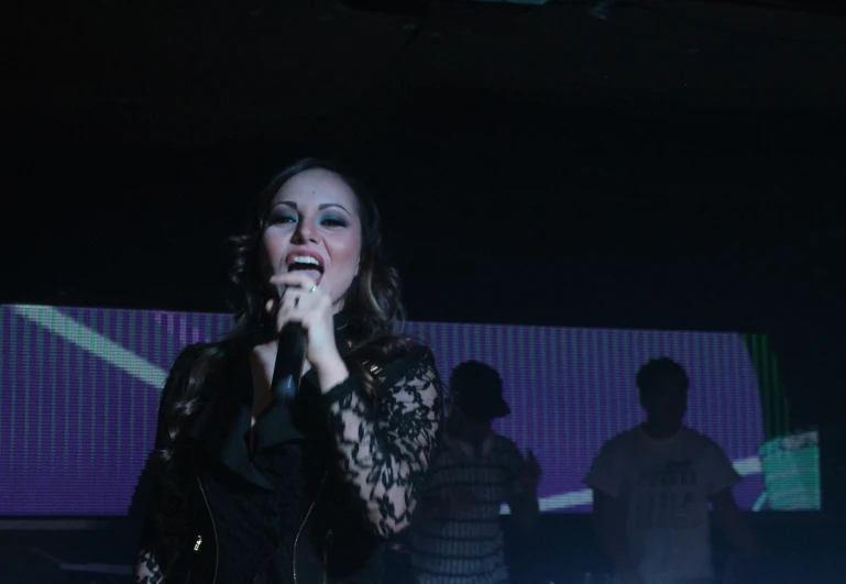 a woman in black shirt on stage with microphone