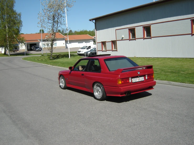 a red car on the street next to a house