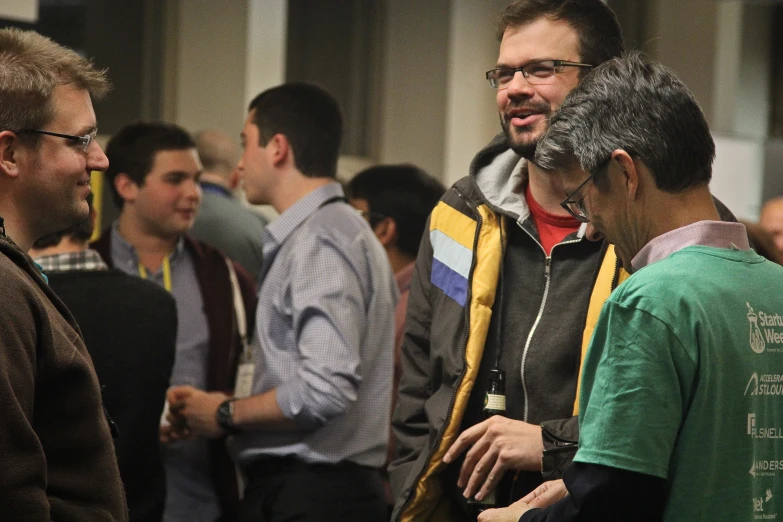 a group of people standing around talking and having drinks