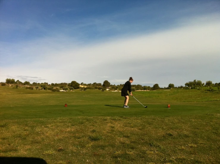 a man standing on a green golf course holding a club