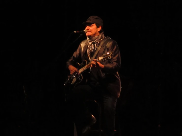 the man is playing his guitar in the dark