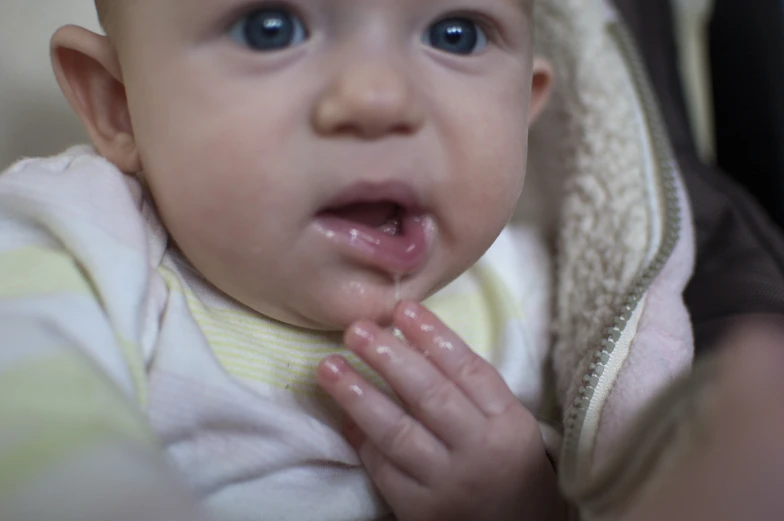 a baby girl is holding her hand up to its mouth