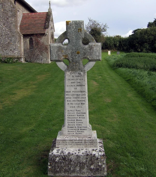 a tall stone cross on the side of a grass covered road