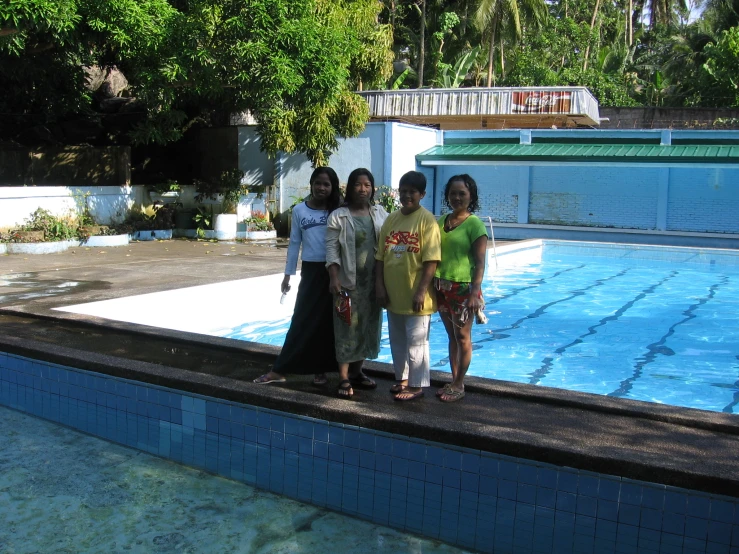 some people standing around a pool by a swimming board