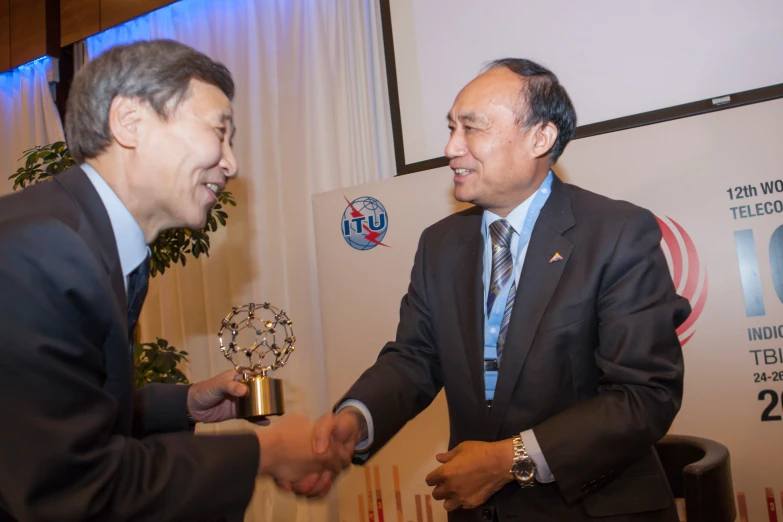 two men shaking hands after winning a business award