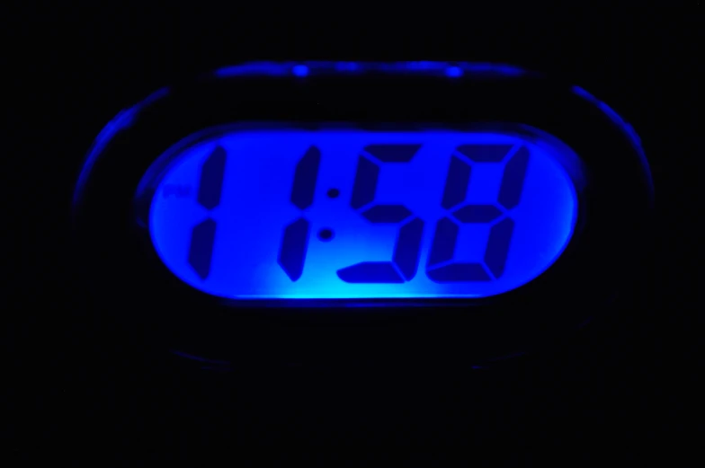 a glowing clock with blue numbers in the dark