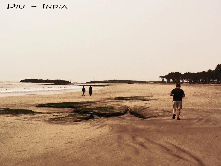 three people are walking along the sandy beach