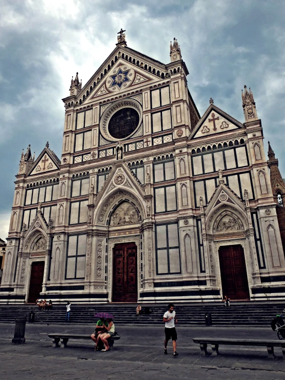 people sitting on benches in front of an old cathedral