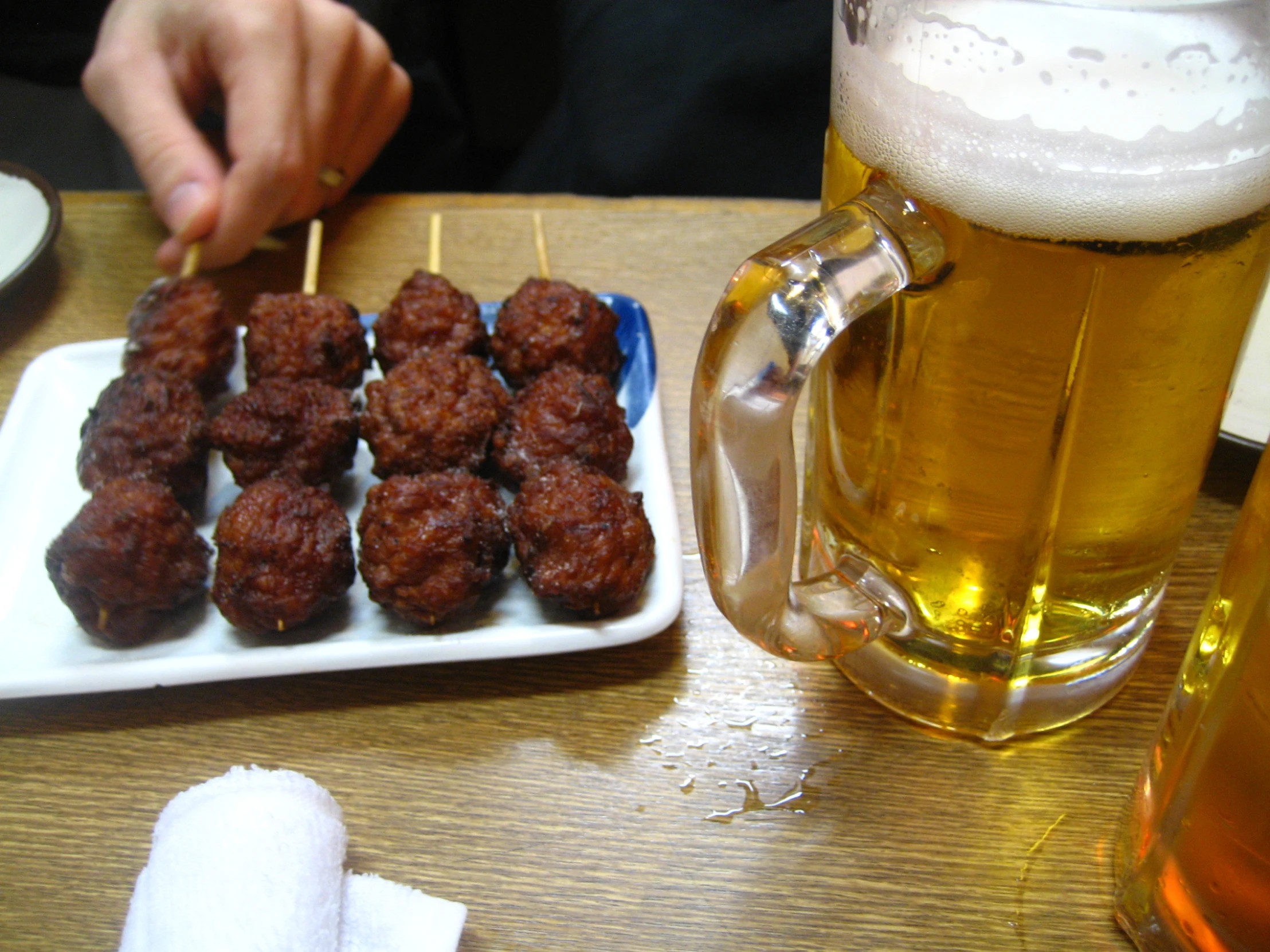 meatballs and beer sit on a plate in front of a mug