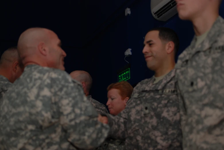 two soldiers hold their arms crossed while talking to an army employee