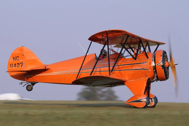 an orange plane in the air going fast